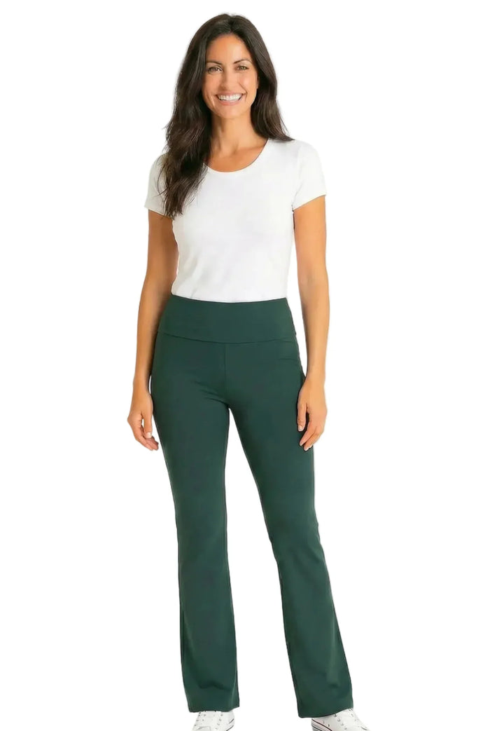 Woman wearing white short sleeve tee and dark green lounge pants, smiling, on white background