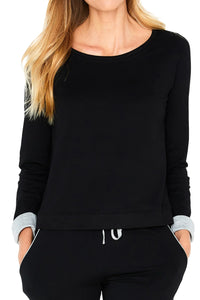Woman wearing black long sleeve Pima cotton lounge top and matching joggers, hands in pockets