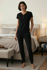 Woman in black Pima cotton loungewear set standing in a cozy bedroom