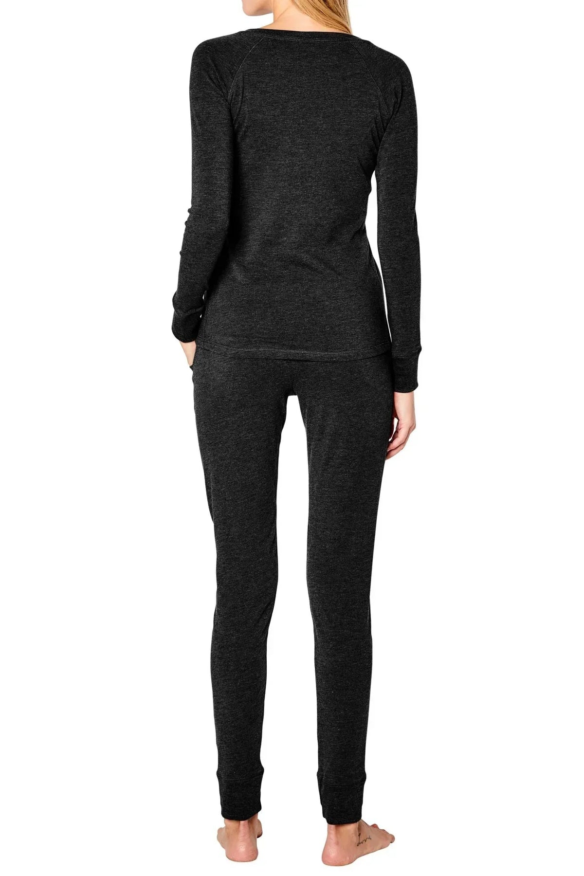 Back view of woman wearing dark grey long sleeve loungewear set, barefoot, on white background