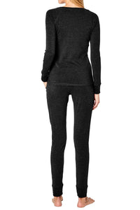 Back view of woman wearing dark grey long sleeve loungewear set, barefoot, on white background