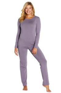 Smiling woman wearing lavender long-sleeve top and lounge pants, barefoot on white background