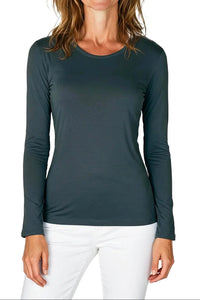 Woman wearing steel blue long sleeve fitted shirt with white pants on white background