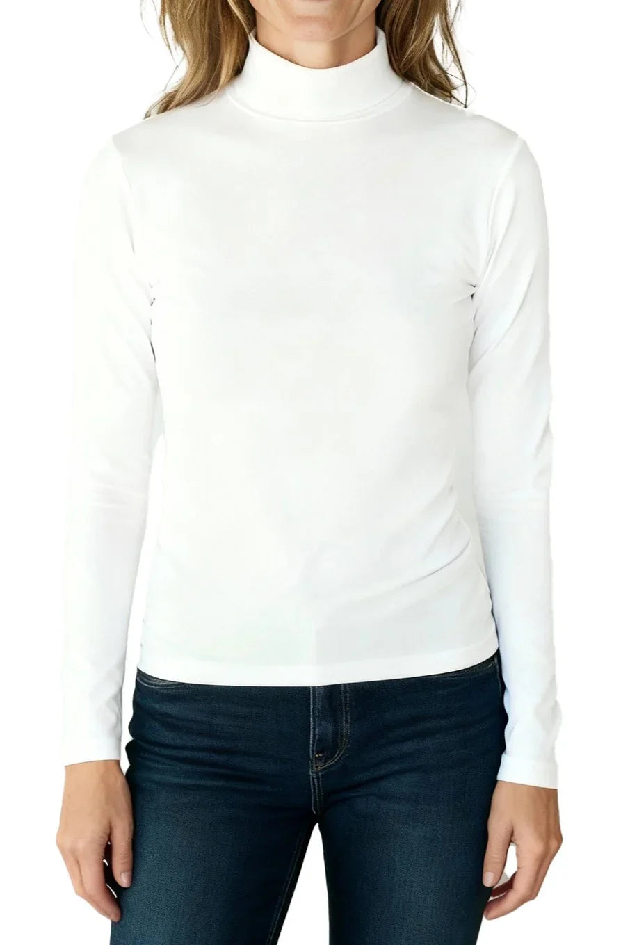 Woman wearing a white long-sleeve mock neck top paired with dark blue jeans