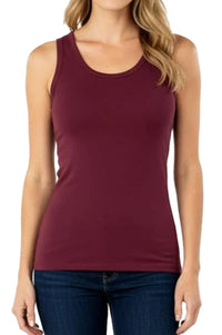 Woman wearing a sleeveless maroon tank top paired with dark blue jeans