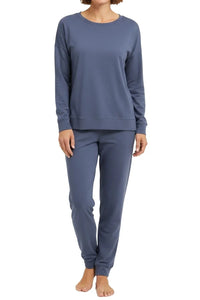 Woman wearing steel blue long sleeve pajama top and matching pants standing barefoot