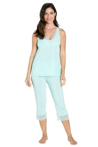 Woman wearing light blue camisole and cropped pants pajama set with lace trim on white background