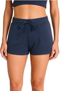 Woman wearing steel blue casual drawstring shorts with front pockets and a matching sports bra